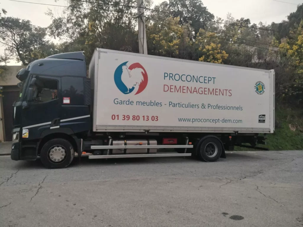 Un technicien Proconcept déchargeant des cartons d’un monte-meuble déployé dans la cour pavée d’une résidence en brique et pierre.