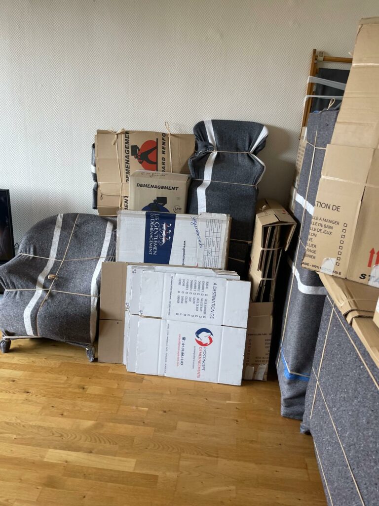 Fauteuils protégés sous couvertures et cartons d'emballage prêts pour le chargement d'un déménagement.