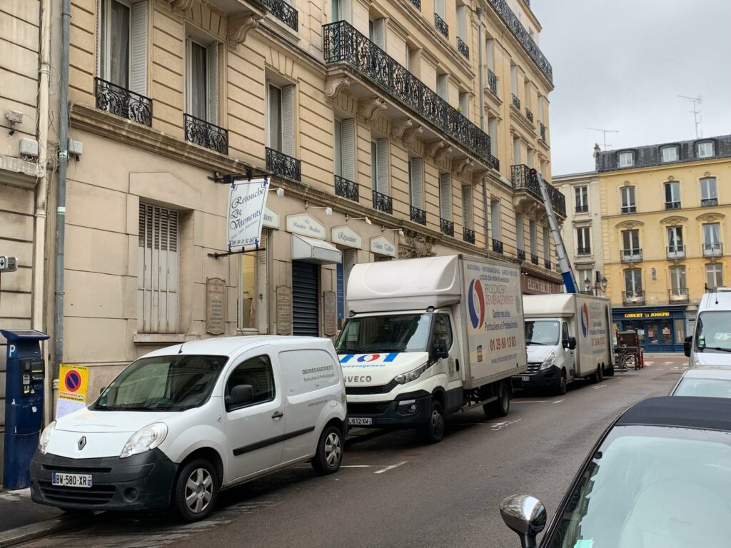 Camions de déménagement Proconcept Déménagements et monte-meuble déployé devant un immeuble haussmannien à Paris, Île-de-France.